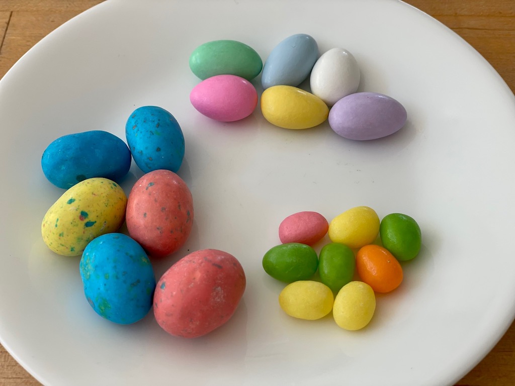 A variety of candy eggs in different sizes: Jordan almonds, SweetTARTs jelly beans, and Whoppers robin eggs.