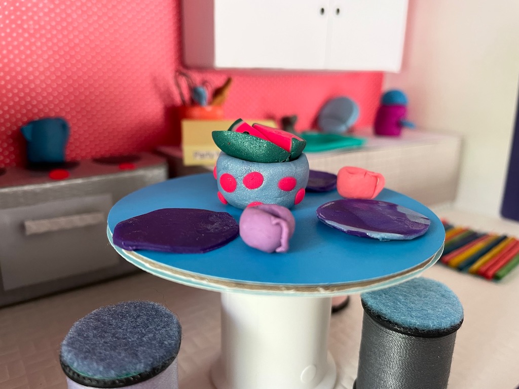 Polymer clay is used to fashion plates, cups, and other kitchen accessories in this homemade dollhouse.