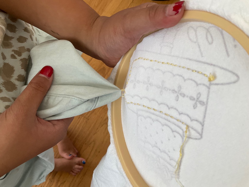 Embroidering is something you can do companionably with a child. This child stitched her skirt to the embroidery by mistake.