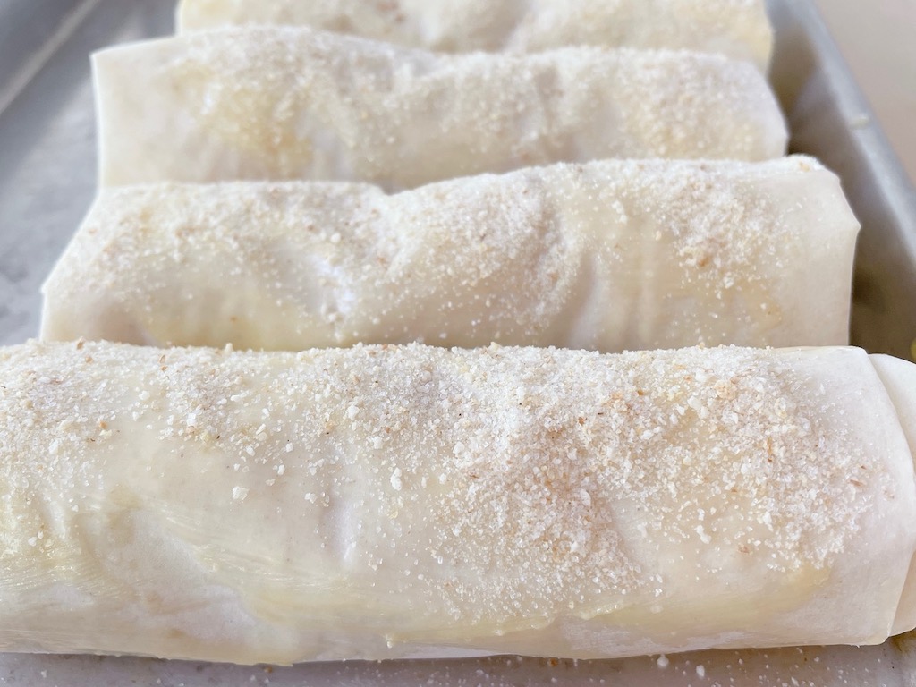 Rolls are buttered and sprinkled with breadcrumb-sugar mixture, ready for the oven.