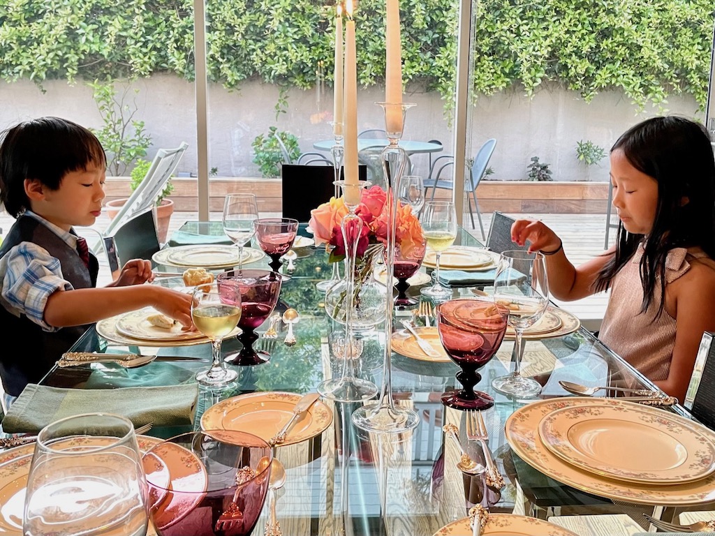 Kids, all dressed up, sit at the table to learn proper dining etiquette.