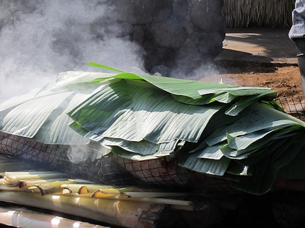 An authentic luau in Kona features a whole pig, wrapped in banana leaves, that will roast in an imu (cooking pit).