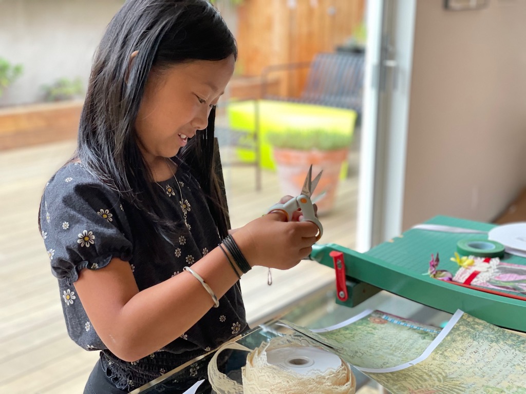 A child trims an image to use in her notebook cover collage.