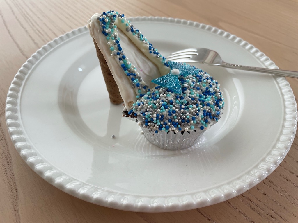 A high heel cupcake is covered with sprinkles and a candy bow.