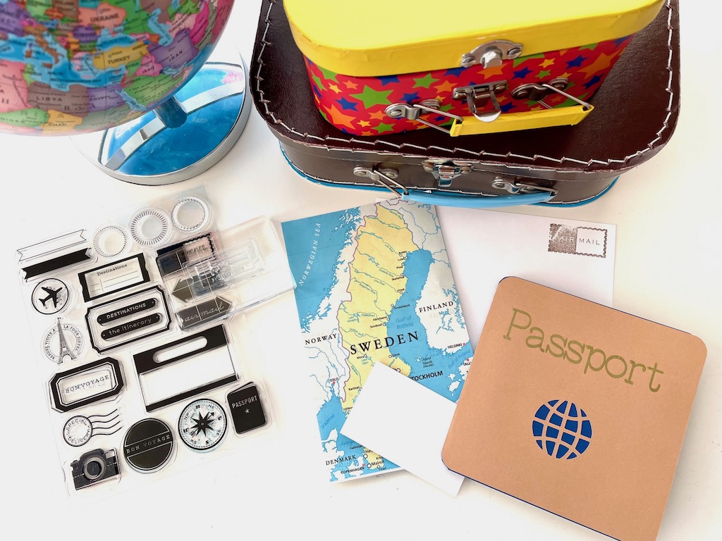 Elements for travel: mini suitcases, map (printed off the Internet), clear travel-related stamps, cardstock for postcards and flag.