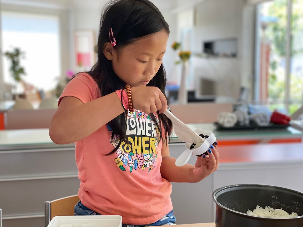 Miss T adds rice into the panda mold using a Japanese rice paddle.