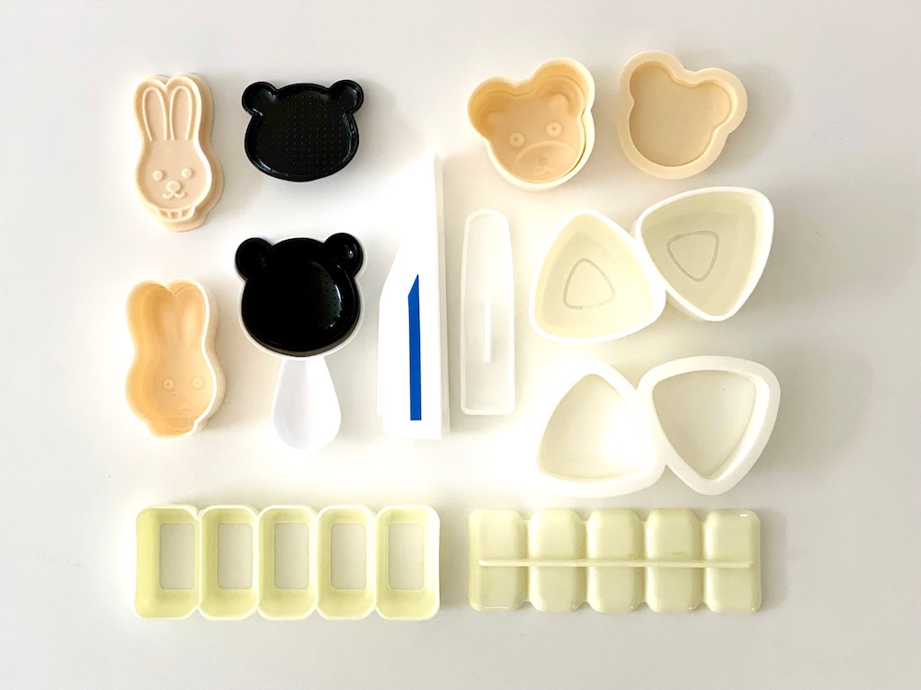 Various molds to make onigiri (rice balls): bunny, panda, bullet train, traditional triangle, and small logs.