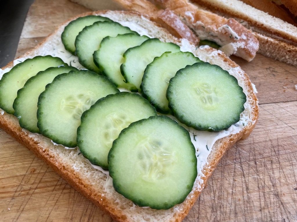 Spread cream cheese on bread slice and top with cucumber slices. Add another slice of bread, trim crusts, and cut sandwiches into rectangles.