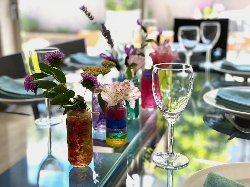 Painted, discarded spice jars, are arranged in the center of the dinner table.