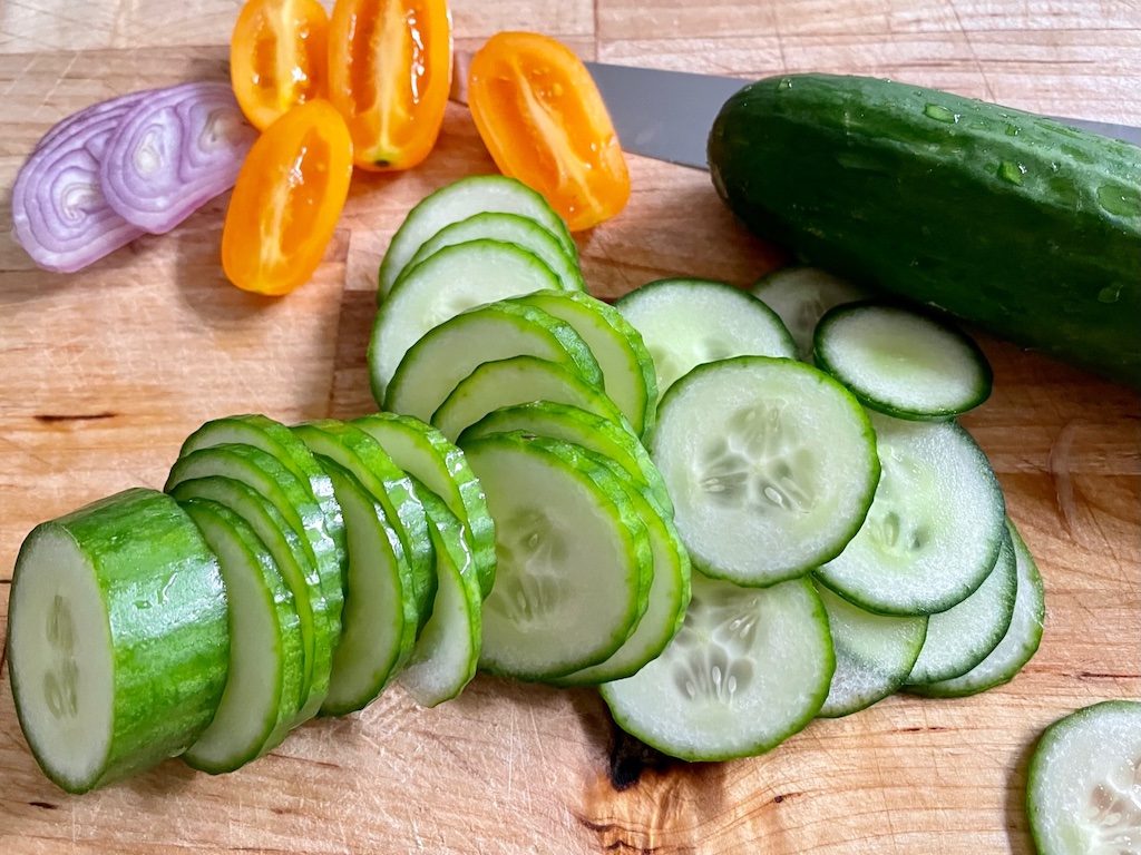 Some of the ingredients used for a Thai-inspired salad: shallots, tomatoes, and cucumber slices.
