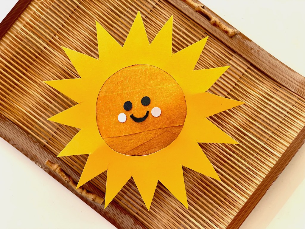 Sun surprise ball has rays cut from cardstock and black and pine hole punches for the eyes and cheeks.