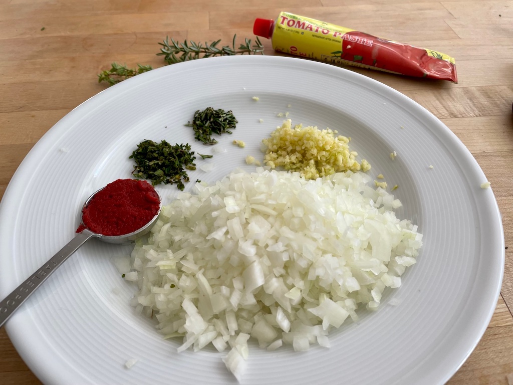 Ingredients for the best, easy meatloaf recipe: onion, tomato paste, thyme, rosemary and garlic.