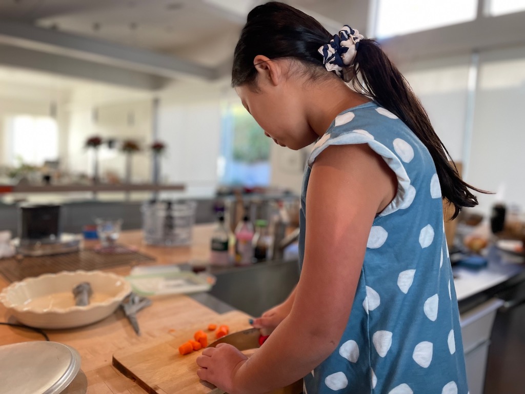 Child cutting vegetables with a child-size chef's knife.