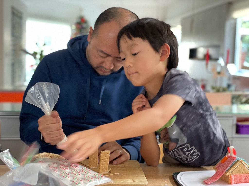 Father and son constructing gingerbread houses.