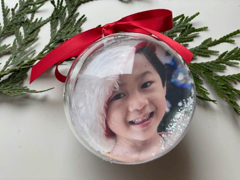 A sample DIY photo Christmas ornament features one grandchild on one side; another grandchild on the second side.