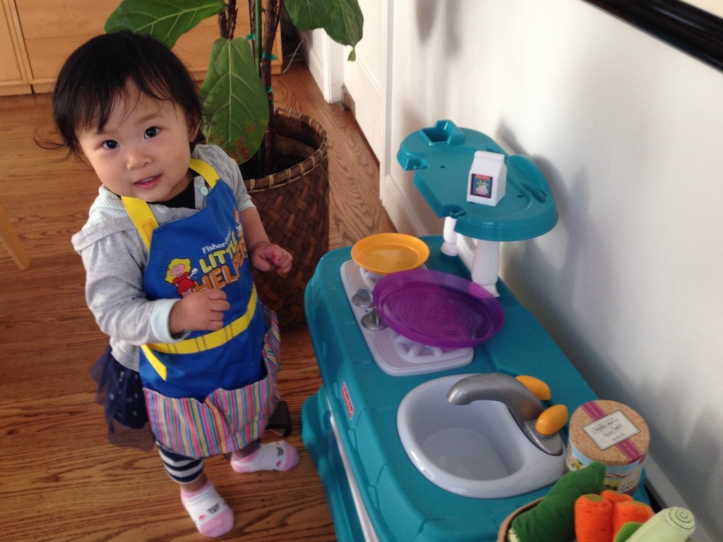 Child playing with a kitchen set. Grandma advice: for best photography, get down to child's level.