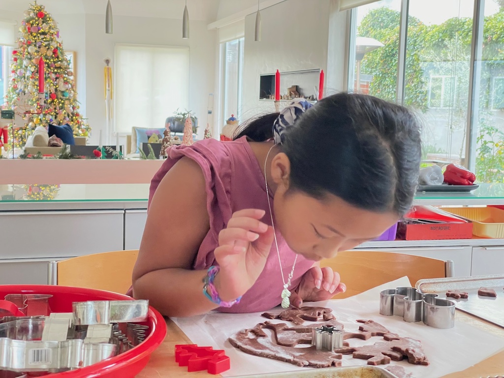 Child cuts out cookies for baking at Christmas time.