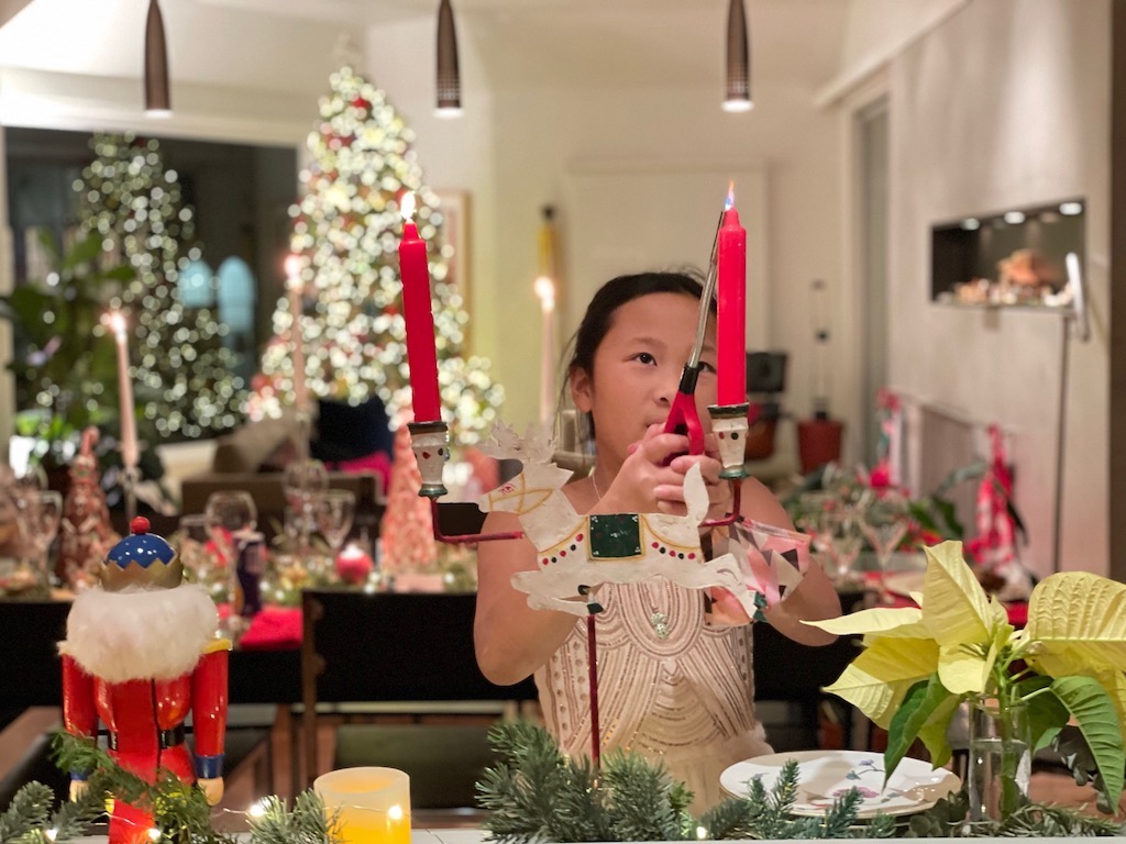 Child lights the candles in preparation for Christmas Eve dinner.