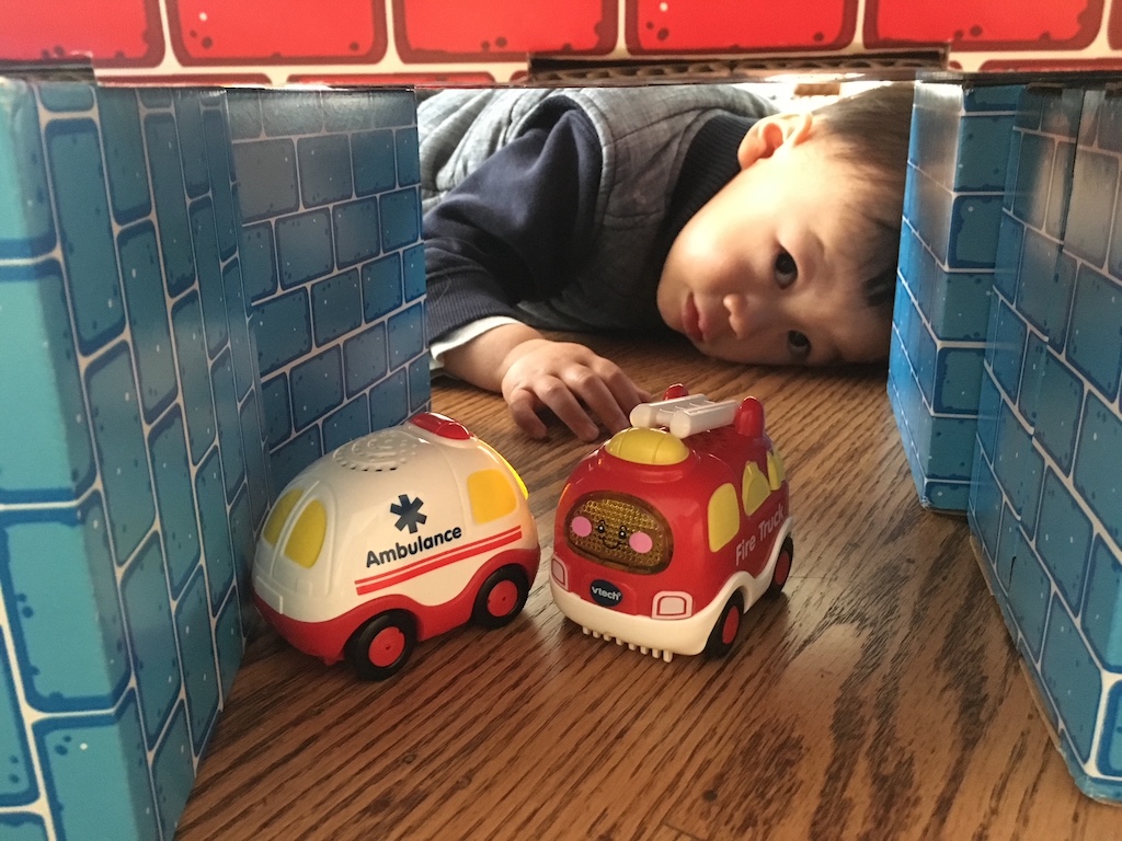 Child playing with ambulance and firetruck; outgrown by first grade.