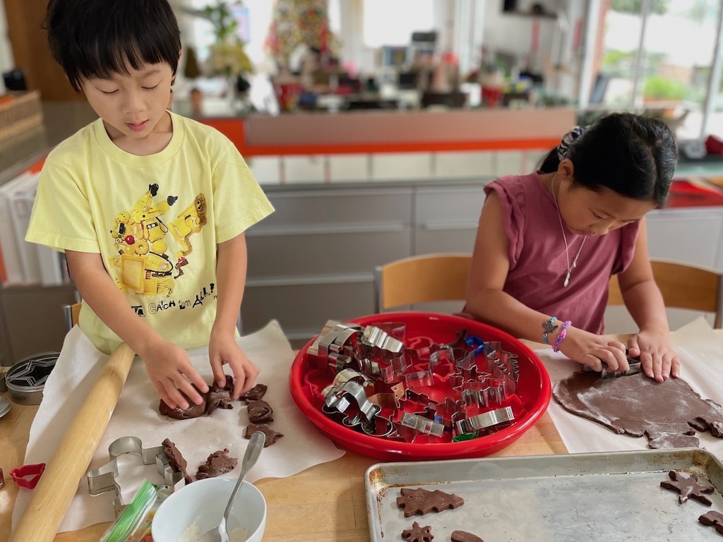 Two children cutting out Christmas cookies as part of the season's family traditions.