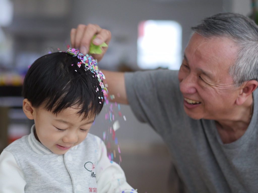 Grandpa crushes a cascarone, Mexican confetti-filled eggs over his grandson's head.