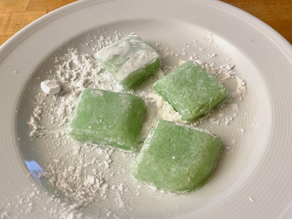 Squares of chichi dango are being coated with potato starch on all sides.