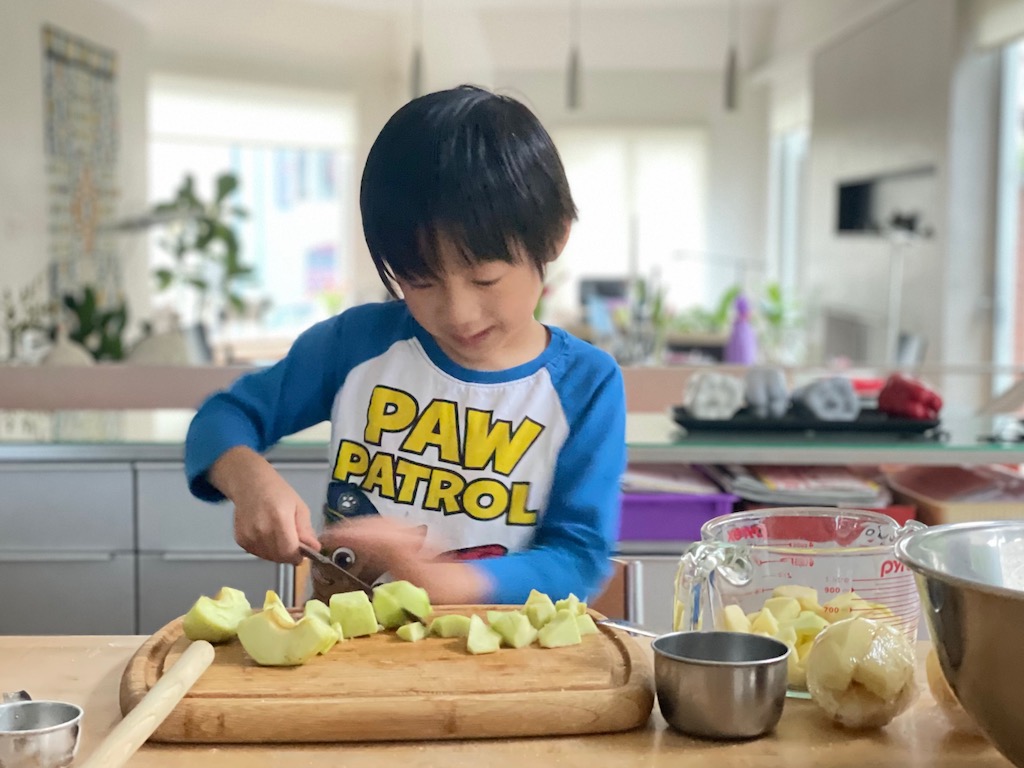 Child uses a table knife to cut apples for Easy Apple Crisp.