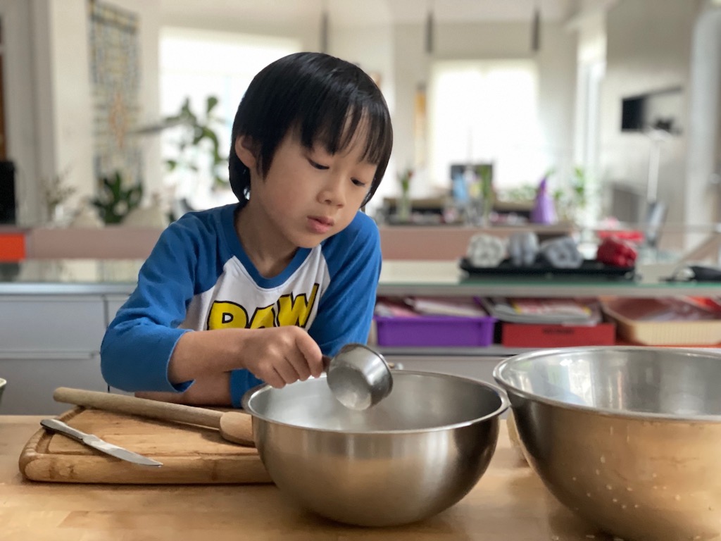Child measures sugar for the topping.
