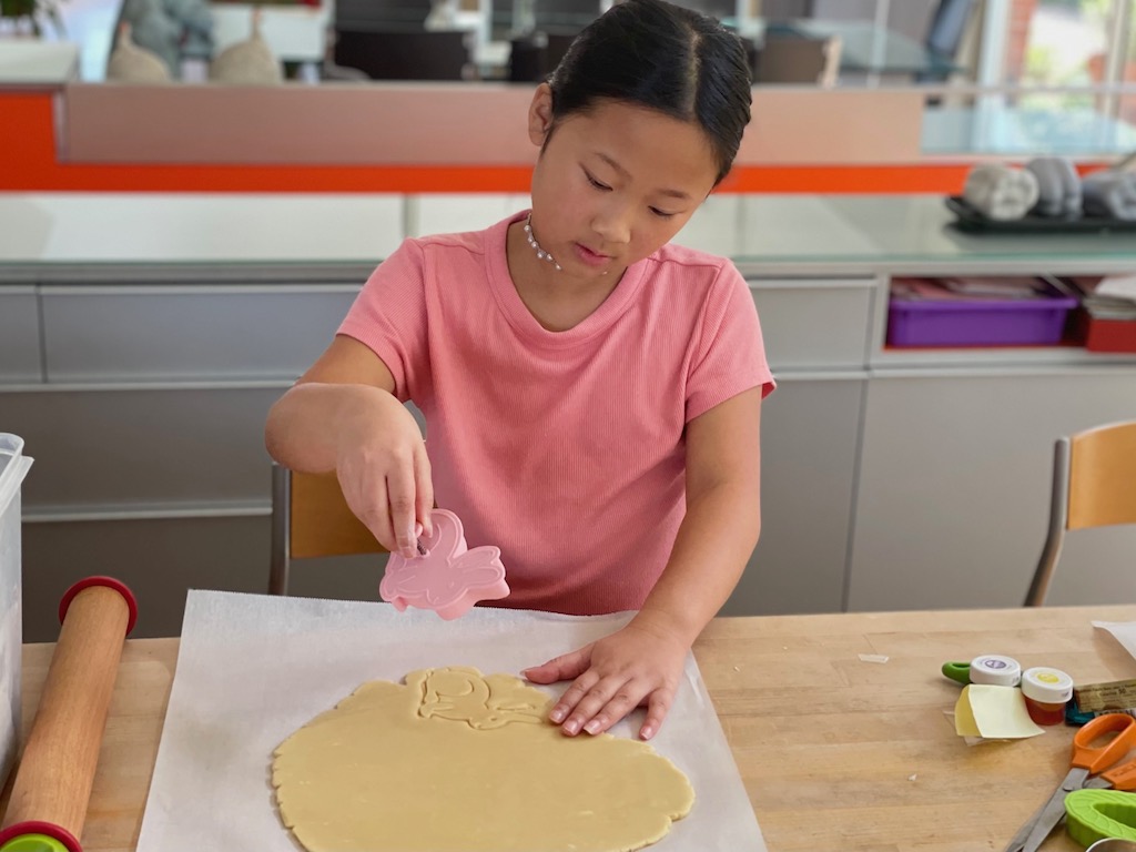 Child cuts a bunny from rolled cookie dough.