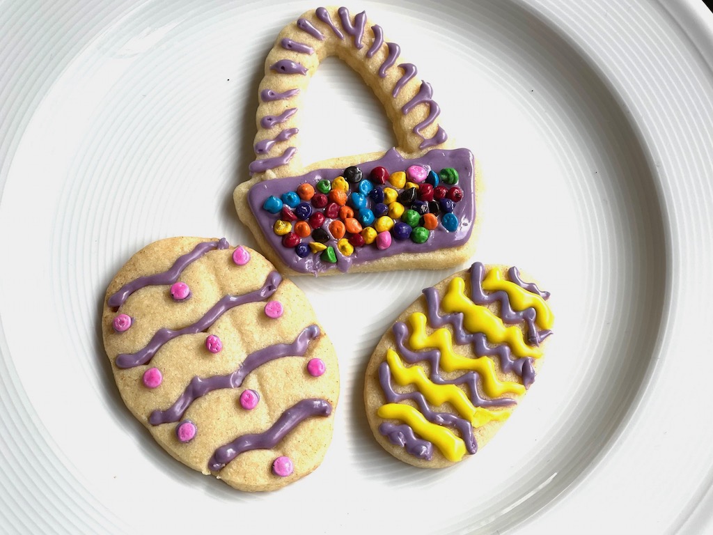 Three decorated cookies: two Easter eggs and an Easter basket.