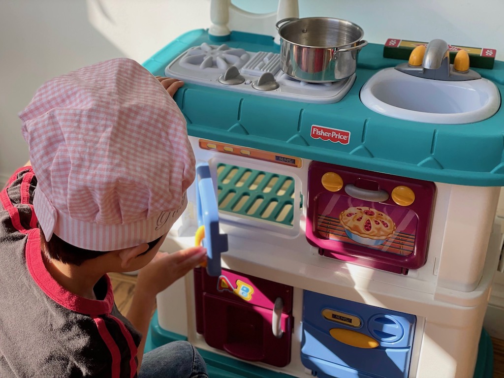 Child playing chef using a toy kitchen set. This was given to a food professional grandma for her toddler grandchild.