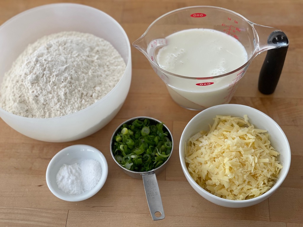 Ingredients for easy Irish soda bread: all-purpose flour, baking soda, salt, green onion, shredded Dubliner cheese, and buttermilk.