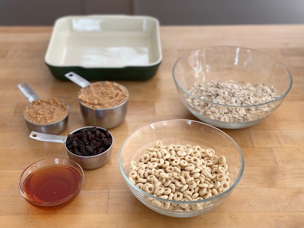 Ingredients for peanut butter cereal bars: honey, raisins, peanut butter, Cheerios, and oats. It takes just five ingredients.