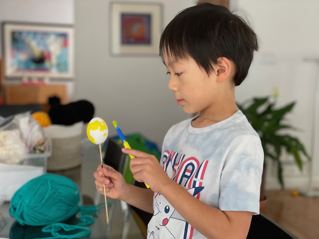 Child paints an egg to make cascarones.