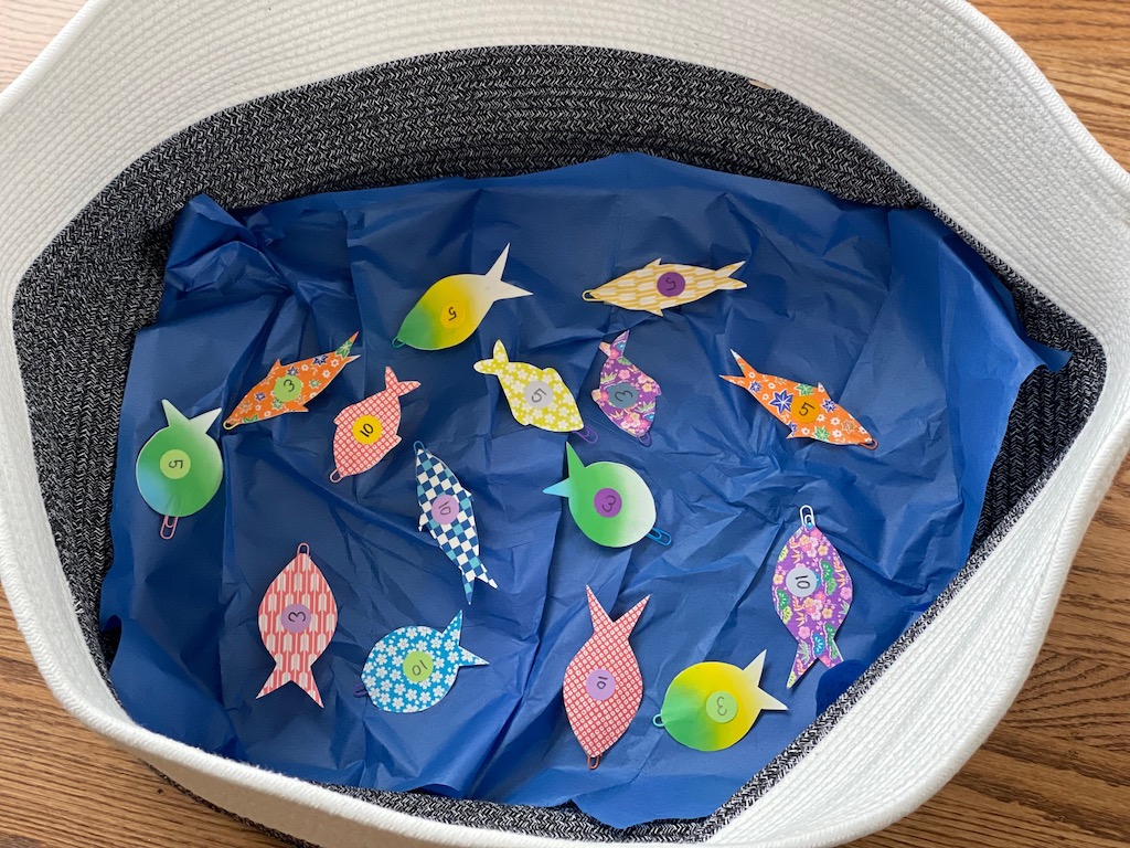 Fish in a basket on blue tissue paper, ready to be caught for this indoor fishing game.