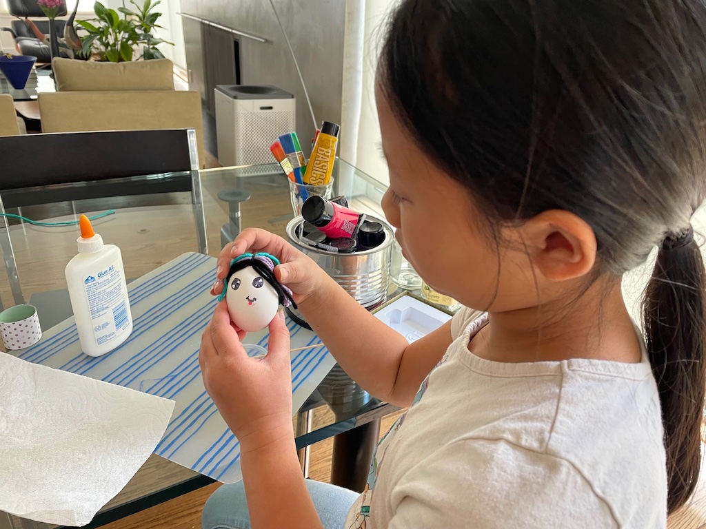 Attach yarn hair to the egg using white school glue.