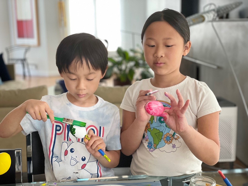 Two children paint eggs for cascarones, Mexican confetti eggs.