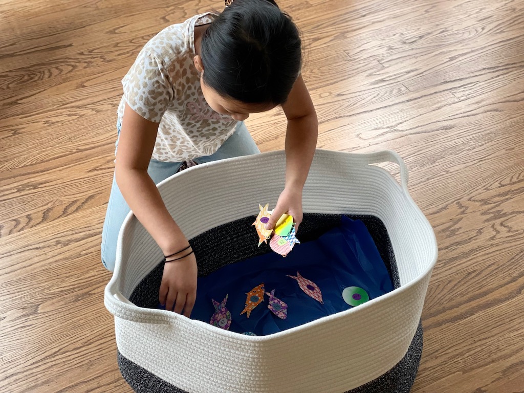 Child lays out the fish in a basket.