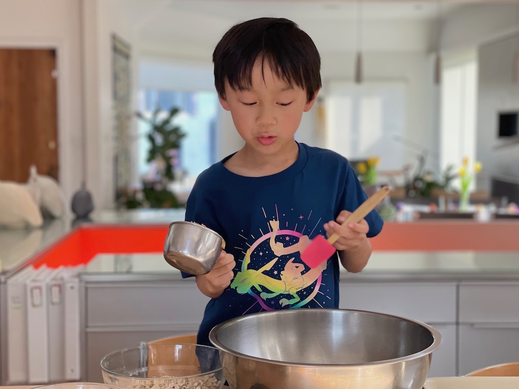 Child mixes ingredients together to make a snack. Making nutritious snacks helps kids to develop healthy eating habits.
