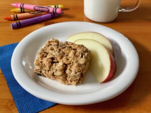 No-Bake Peanut Butter Cereal Bars is served with apple slices and a glass of milk.