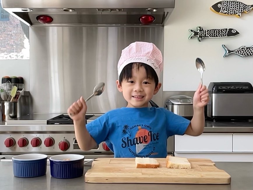 A child in the kitchen ready to demo how to make a peanut butter and jelly sandwich for a cooking video.