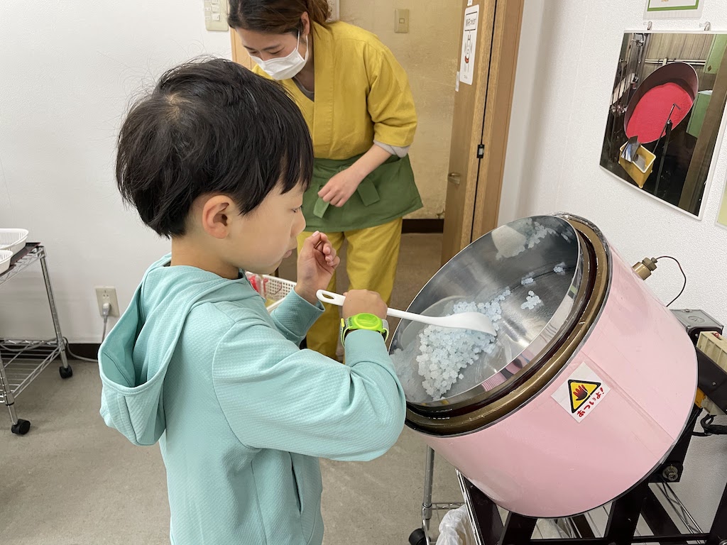 A fun activity traveling with kids in Osaka is making kompeito candy. A child stirs up his candy concoction.