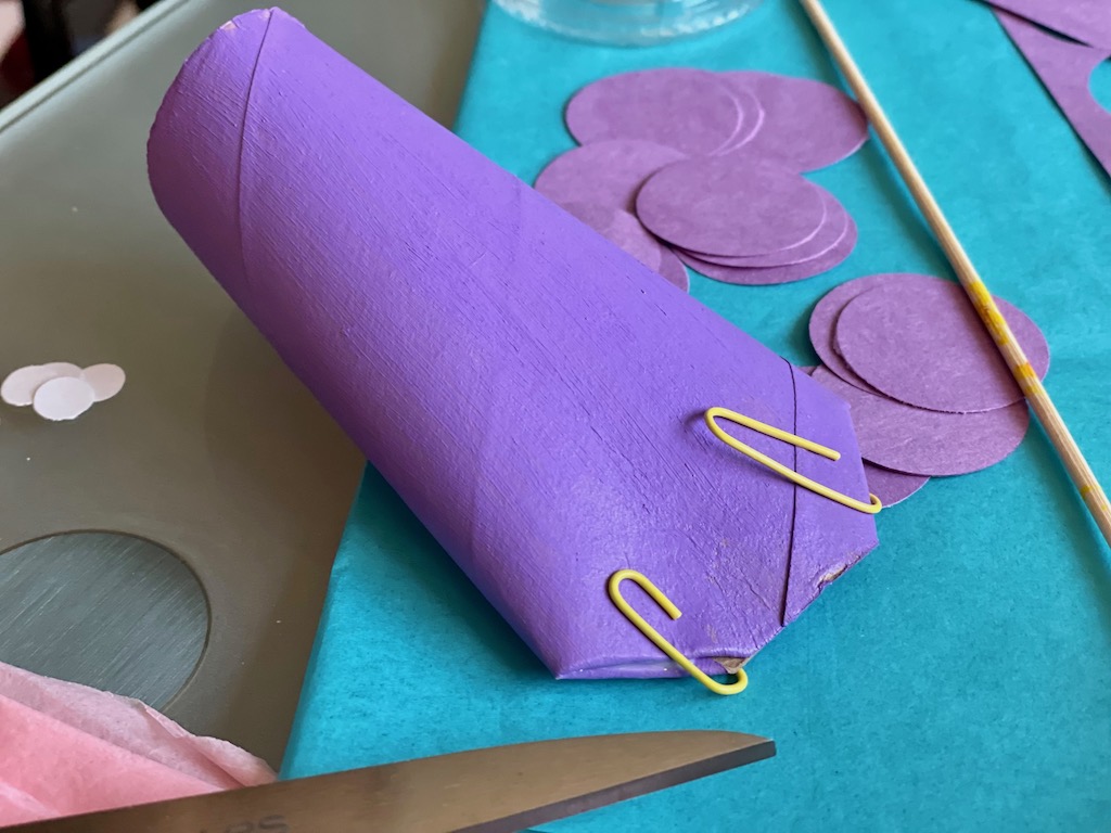 To make a shaped fish head, snip the toilet paper roll and fold ends in on a diagonal. Glue with white school glue and hold in place with paper clips until glue dries.