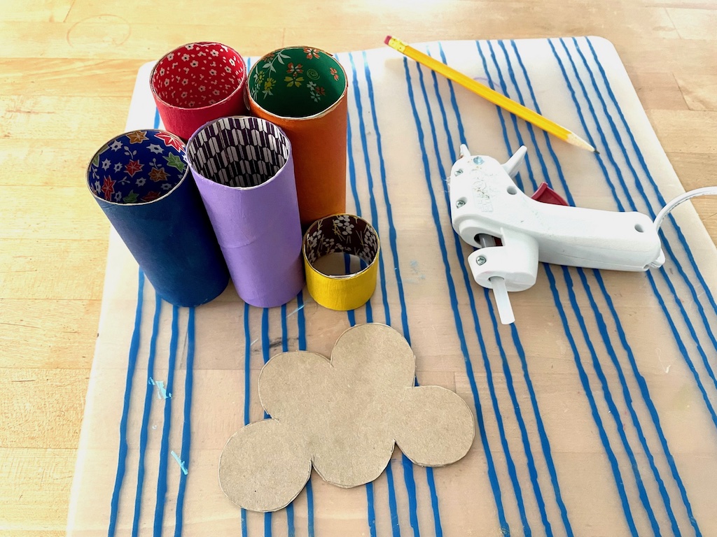 Glue the toilet paper rolls together using a glue gun. Then trace the shape of the glued-together rolls onto cardboard, to make a base.