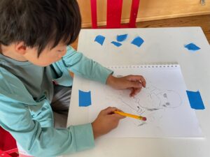 Child traces image from coloring page to practice pencil-holding skills.