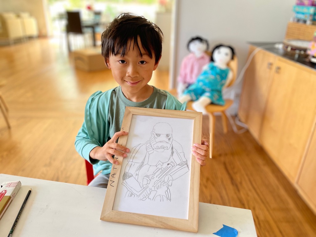 Child and his art tracing of a storm trooper. This is a way to practice small motor skills by tracing over lines to create the image.