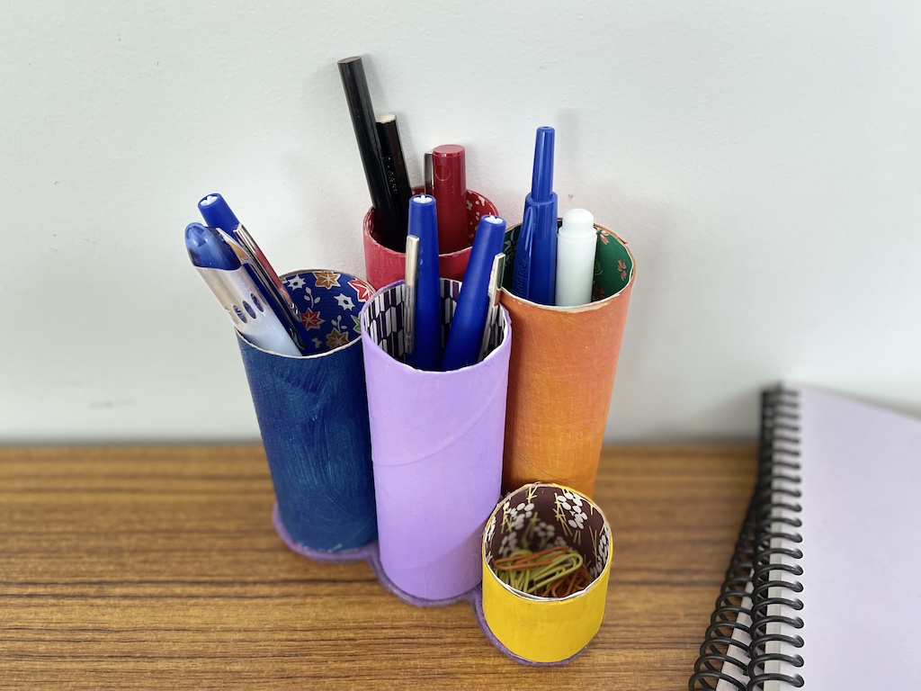 This DIY gift for dad is made of toilet paper rolls, painted, lined in origami paper, and glued to a felt-covered cardboard base.