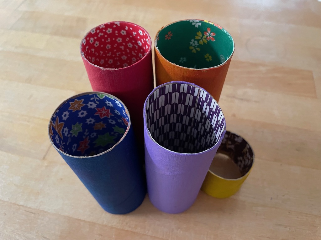 Lining the toilet paper rolls with origami paper hides any paint splotches that may have landed on the inside of the roll.