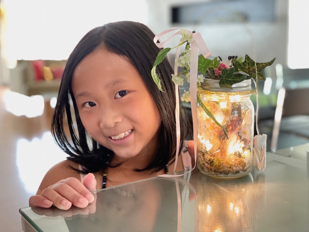 Craft projects help to entertain kids when stuck indoors during a heat wave. Child makes a fairy lantern while keeping cool.