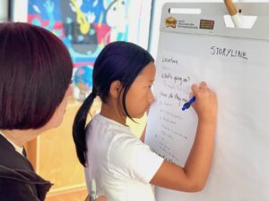 child serves as scribe to brainstorm ideas for writing a script.